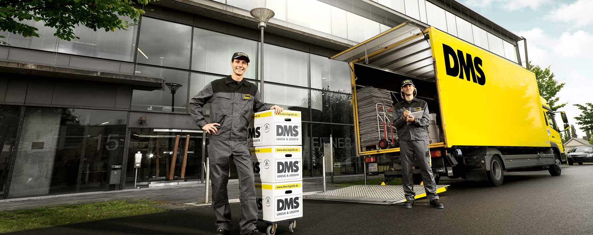 Zwei Mitarbeiter stehen vor einem Bürogebäude und führen einen Büroumzug in Hamburg durch. 